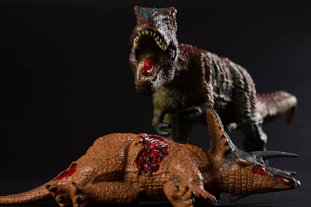 тираннозавр с телом трицератопса поблизости на тёмном фоне
 - Фото, изображение