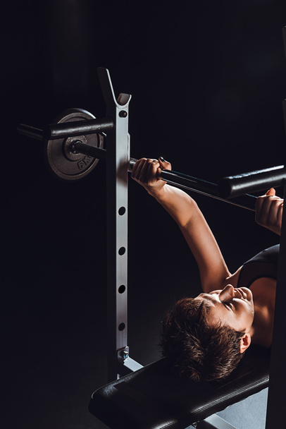 kadın vücut geliştirmeci halter, spor salonu, siyah arka plan ile egzersiz yaparak yüksek açılı görünüş  - Fotoğraf, Görsel