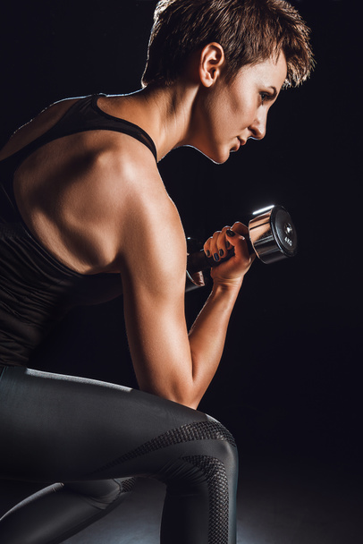 kadın atlet spor salonu, siyah arka plan, dumbbell ile egzersiz yan görünüm  - Fotoğraf, Görsel