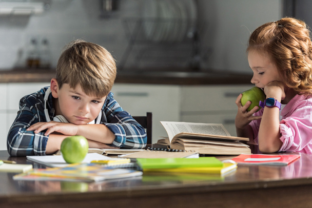 little brother and sister with green apples doing homework - Photo, Image
