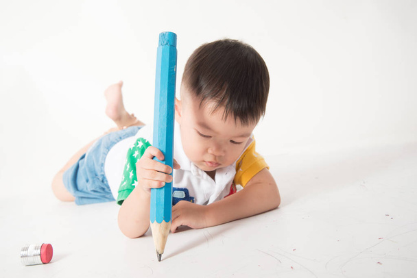 白い背景の上の手で大きな鉛筆で幼児男の子の赤ちゃん - 写真・画像