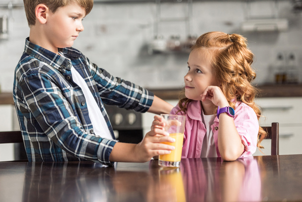 little brother giving glass of orange juice to his sister - Φωτογραφία, εικόνα