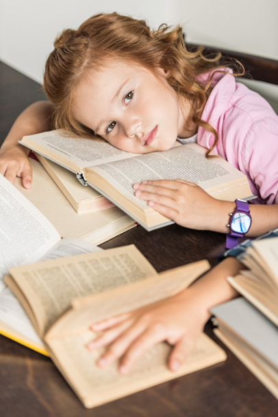 high angle view of exhausted little schoolgirl lying on books - Foto, imagen