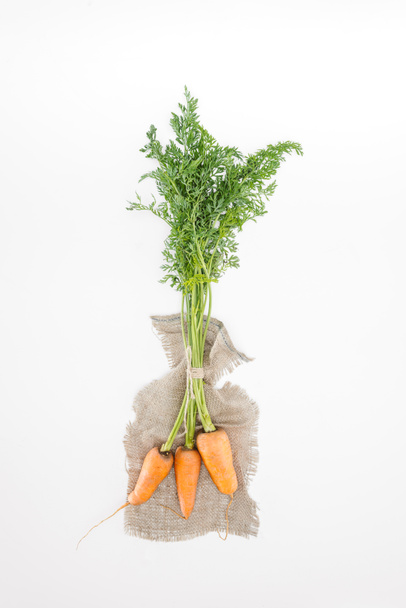 top view of fresh carrots tied with rope on sackcloth isolated on white - Фото, зображення