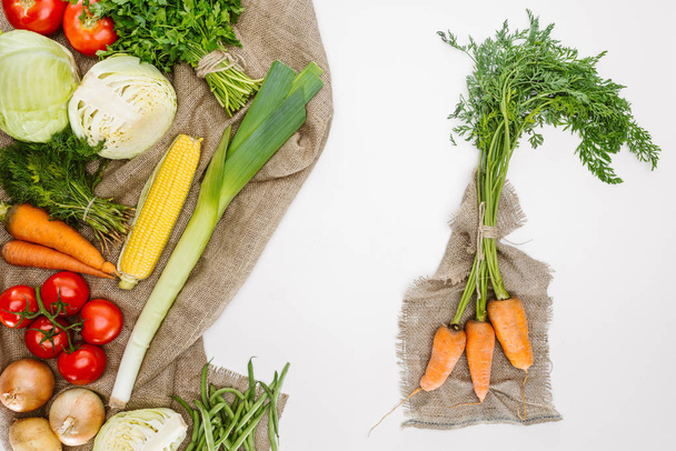 Nahrungsmittelzusammensetzung mit frischem Gemüse auf Sacktuch isoliert auf weiß angeordnet - Foto, Bild