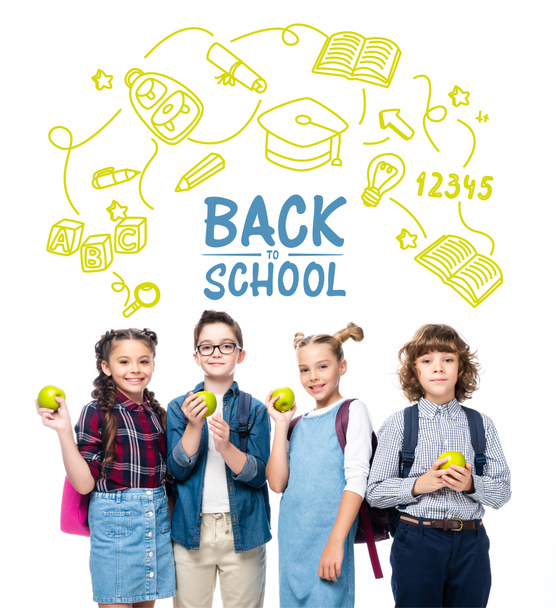 usmívající se školáci drží zralá jablka izolované na bílém s ikonami a písmem "zpátky do školy" - Fotografie, Obrázek