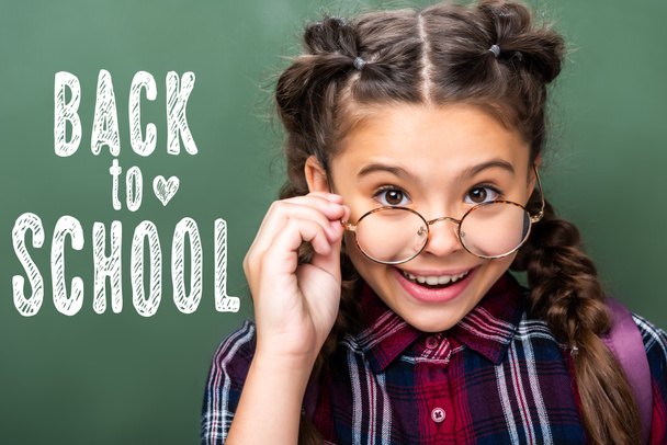 ritratto di scolaro che guarda sopra gli occhiali vicino alla lavagna, con scritte "torna a scuola"
 - Foto, immagini
