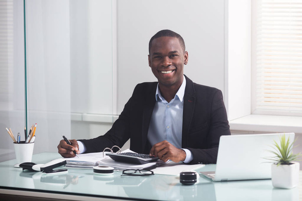 Happy African Businessman Looking At Laptop Calculating Invoice In The Office - Foto, Imagem