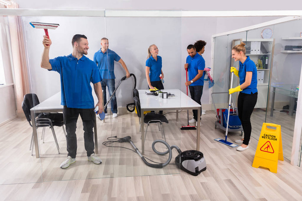 Group Of Skilled Young Janitors In Uniform Cleaning Office - Foto, afbeelding