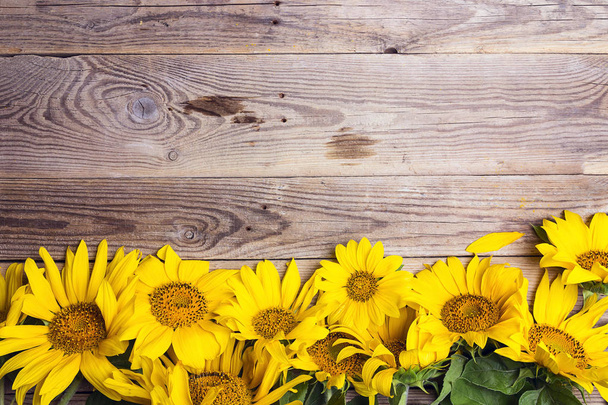 Yellow sunflowers on old wooden background. Copy space. Top view. - Fotó, kép
