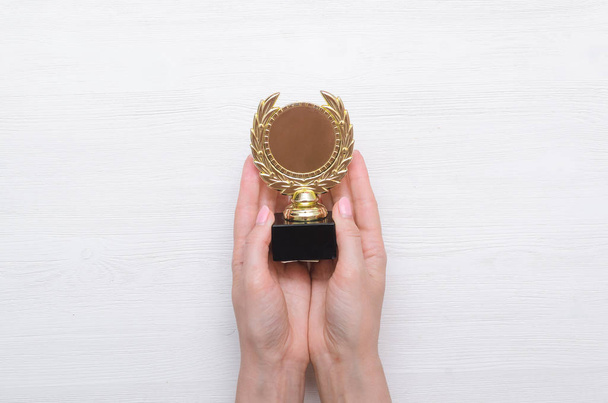 Golden medal award trophy in the female hand. Winner award ceremony. - Foto, imagen