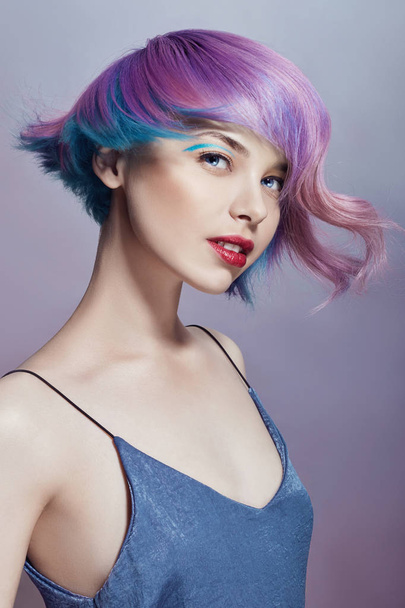 Portrait of a woman with bright colored flying hair, all shades of purple. Hair coloring, beautiful lips and makeup. Hair fluttering in the wind. Sexy girl with short  hair. Professional coloring - Foto, Bild