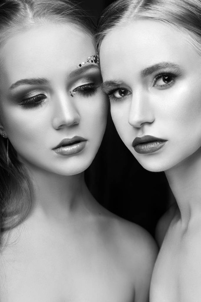 Art makeup two girls hugging, lots of rhinestones of different shapes, beautiful face smooth skin care. Beauty makeup on the face of two women close-up. Professional makeup artist, long beautiful hair - Фото, зображення