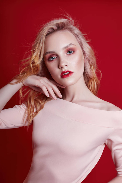 Sexy fashion blonde with bright red makeup on bright red background. Girl in lingerie body with a perfect figure. Professional make-up, skin care, natural cosmetics for face, beautiful eyes - Zdjęcie, obraz