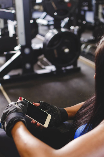 Young woman at gym taking a break and looking at her smartphone. - Foto, Imagem