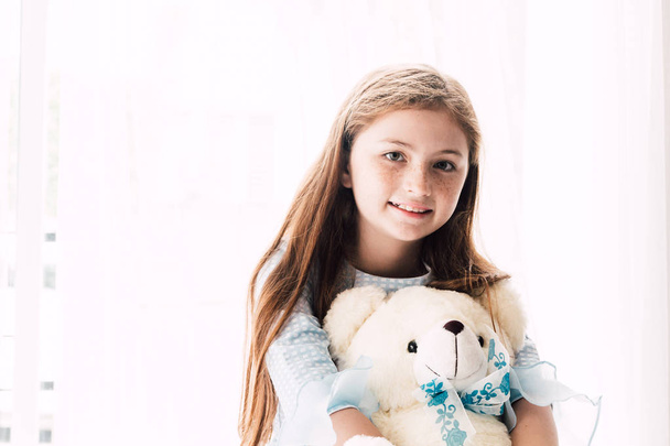 Roztomilá holka holčička objímání medvídky na posteli doma - Fotografie, Obrázek
