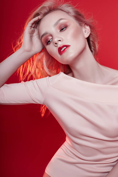 Sexy fashion blonde with bright red makeup on bright red background. Girl in lingerie body with a perfect figure. Professional make-up, skin care, natural cosmetics for face, beautiful eyes - 写真・画像