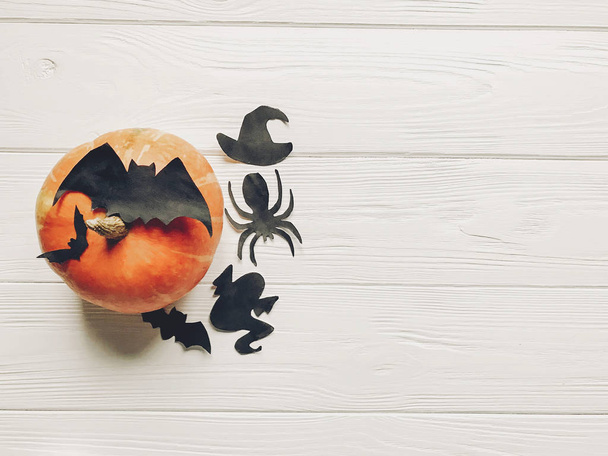 Halloween flach lag. Happy-Halloween-Konzept. Kürbis mit Hexengeist-Fledermäusen und spinnenschwarzen Dekorationen auf weißem Holzhintergrund von oben mit Platz für Text. Saisongrüße - Foto, Bild