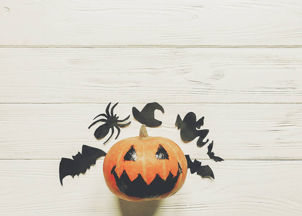 halloween. jack lantern pumpkin with witch ghost bats and spider black decorations on white wooden background top view. seasonal greetings. happy halloween concept, space text - 写真・画像
