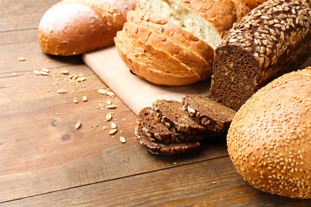 Sor különböző friss kenyér, egy fából készült háttér. Koncepció kenyér - Fotó, kép