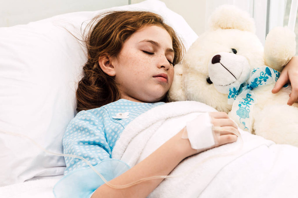 Alszik az ágyon keresztül a kórházi intravénás gyógyszert a beteg kislány - Fotó, kép