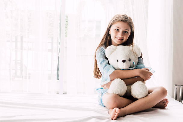 Petite fille mignonne enfant étreignant les ours en peluche sur le lit à la maison
 - Photo, image