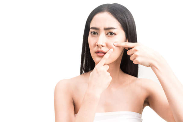 Mujer joven con acné apretando espinilla de su rostro. Cuidado de la salud belleza. Tratamiento del acné. Piel fresca perfecta aislada sobre fondo blanco
 - Foto, imagen