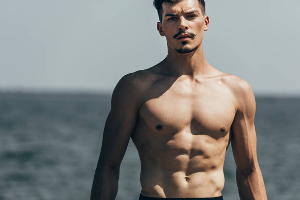handsome athletic man looking at camera in front of sea - Photo, Image
