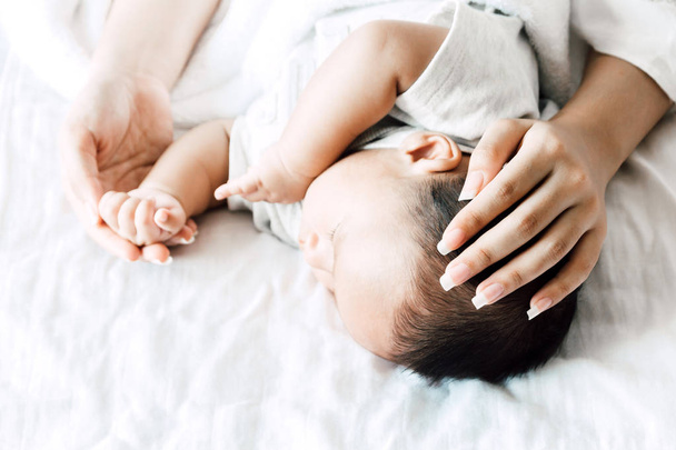 Anya gazdaság alvó baba kezét, fehér ágy. Szerelem a járműcsalád-koncepció - Fotó, kép