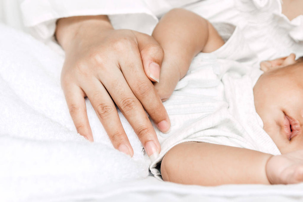 Мать, держащая спящего младенца за руку на белой бороде
 - Фото, изображение