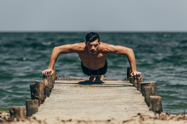 gönderme yapan yakışıklı atletik erkek ups ahşap iskele üzerinde - Fotoğraf, Görsel