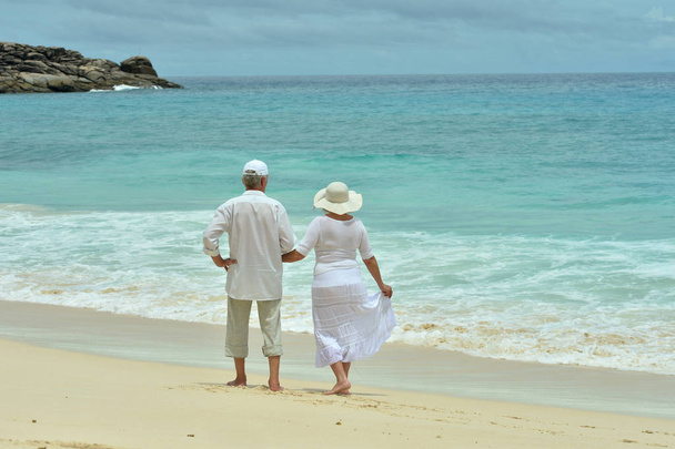 bejaarde echtpaar rusten op tropisch strand - Foto, afbeelding