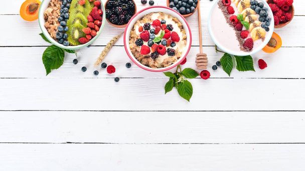 Large Assortment of porridge with fruit and berries. Breakfast. On a white wooden background. Top view. Free space for text. - Fotoğraf, Görsel