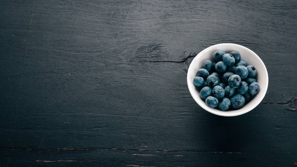 Blueberries Fresh berries in the plate.On the black wooden background. Free space for text. - Foto, Imagen
