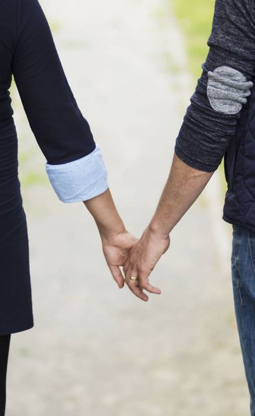 junges Paar schlendert Händchen haltend durch den Park - Foto, Bild