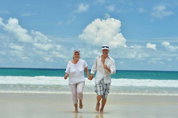 feliz casal de idosos correndo na praia tropical
  - Foto, Imagem