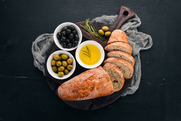 Olives and bread. Italian cuisine. On a wooden table. Top view. Free space for text. - Fotografie, Obrázek