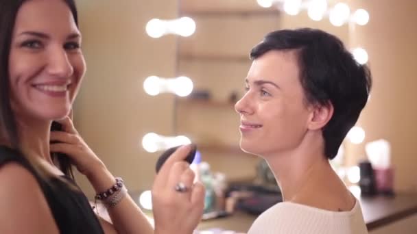 Modello e make-up artist sorriso nel processo di applicazione di una crema di fondazione
 - Filmati, video