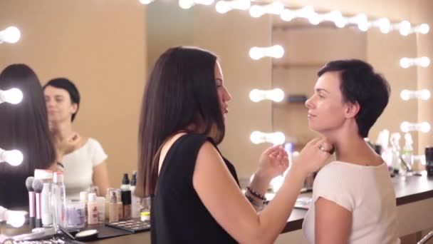 Modello e make-up artist sorriso nel processo di applicazione di una crema di fondazione
 - Filmati, video