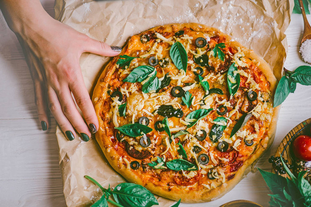 Рука берет ломтики пиццы с белого деревянного фона. Пицца и руки закрыть на белом фоне
 - Фото, изображение