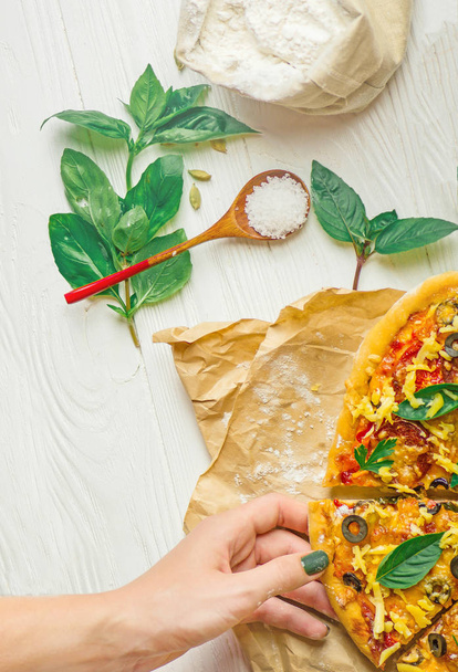 Hand nemen pizza segmenten van witte houten achtergrond. Pizza en hand close-up op witte achtergrond. Vrije ruimte op tafel - Foto, afbeelding