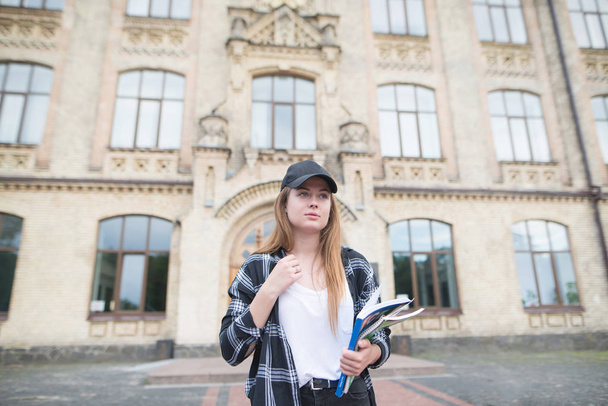 Linda estudiante caminando en el campus con libros y libros en sus manos. Retrato de un estudiante atractivo en ropa casual
. - Foto, imagen
