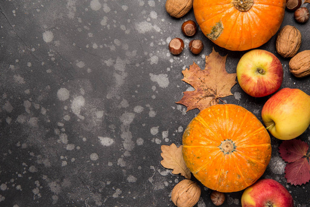 Apples, pumpkins,hazelnut, walnut and fallen leaves on dark background. Copy space for text, top view. Thanksgiving background - Valokuva, kuva