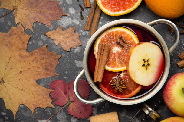 Preparation of red mulled wine with orange, Apple, cinnamon, tub, spicy autumn drink in the pan. Copy space for text, top view. Dark background - Φωτογραφία, εικόνα