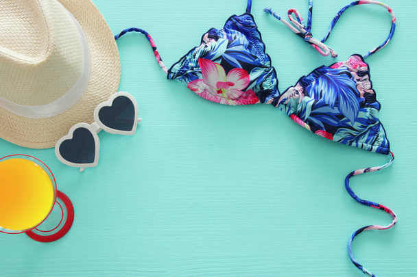 Vista superior del bikini de traje de baño femenino de moda y sombrero de fedora blanco sobre fondo de madera de menta. Verano playa vacaciones concepto
 - Foto, imagen