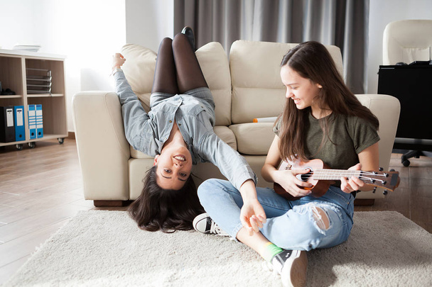 Two sisters in the living room having fun - Фото, изображение