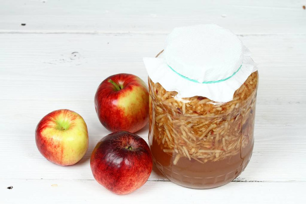 Handmade apple vinegar from organic red apples. Grated apples with peels, water with a little sugar in the bottle covered with paper tissue - Photo, Image