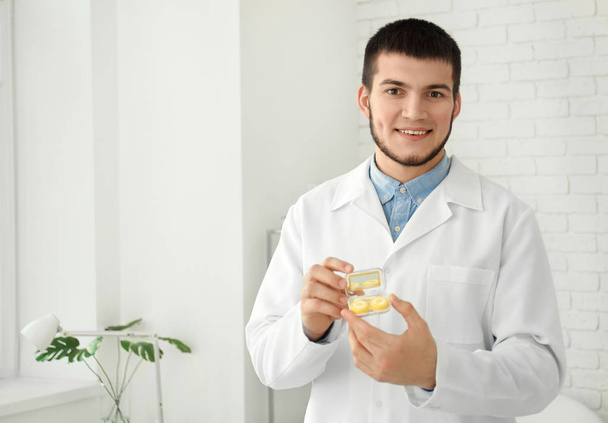 Doctor holding plastic container with contact lenses in clinic - Фото, изображение