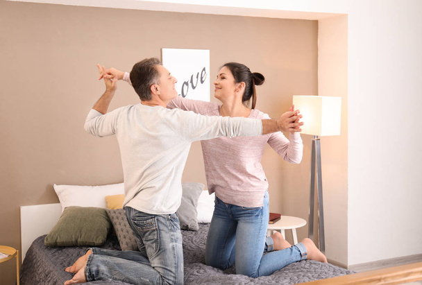 Lovely couple dancing on bed together at home - Foto, Imagen