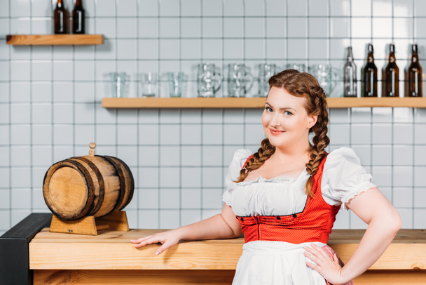 vonzó oktoberfest pincérnő a hagyományos bajor ruha áll közel, hordó sör inspirációk  - Fotó, kép